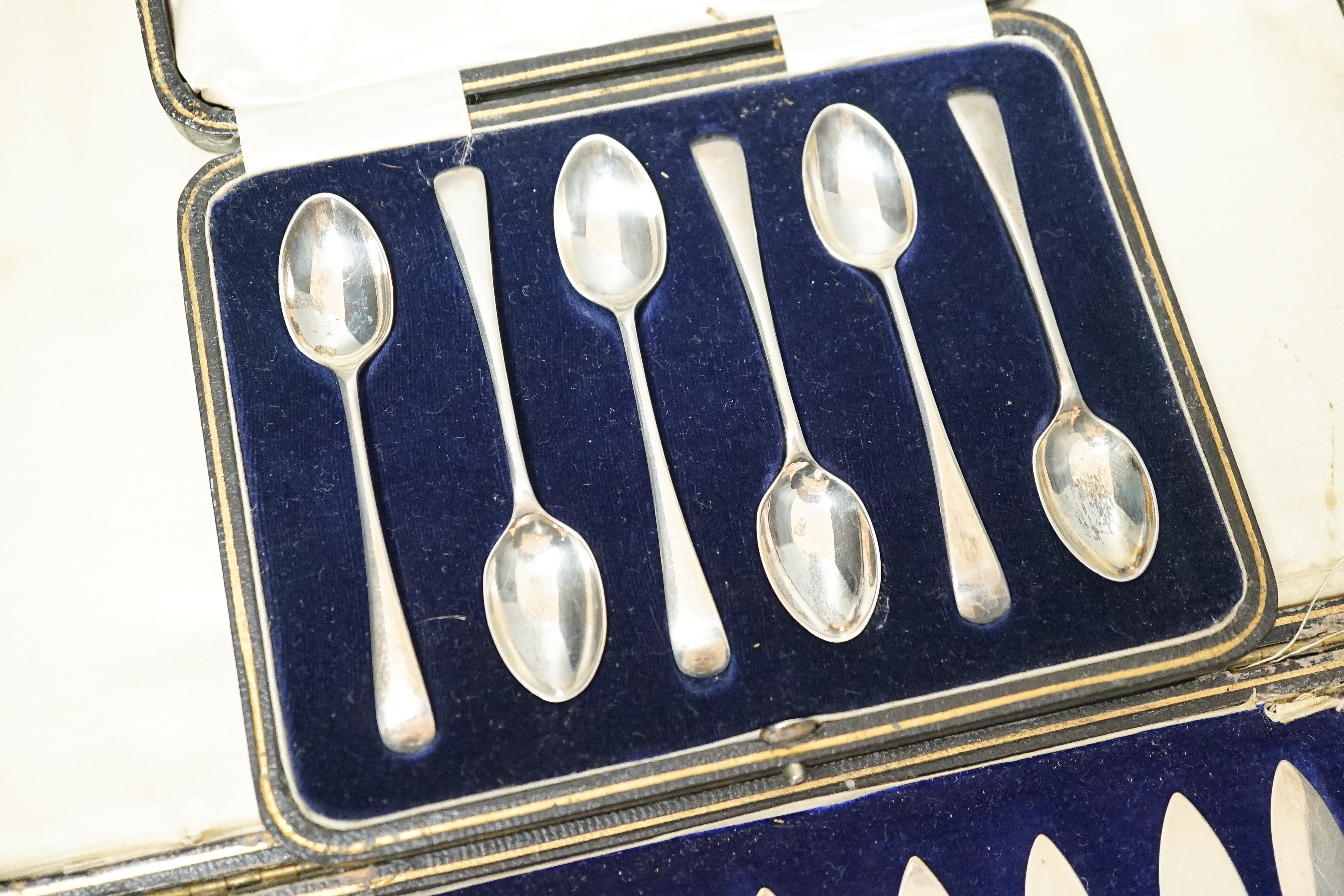 A cased set of twelve reeded silver pistol handled steel dessert knives and a cased set of six silver teaspoons.